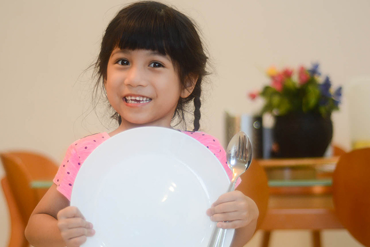 Chantry, 5 years old, showing a plate and utensils.